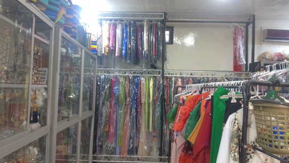 Rails of clothing in the boutique beside a glass case of jewellery