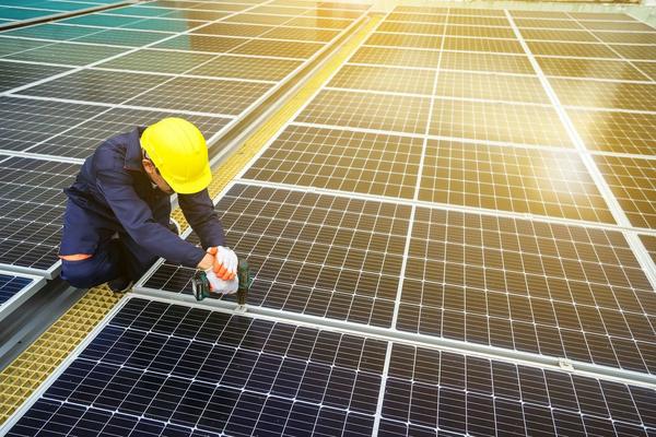 Installer in a hard hat working on a solar array